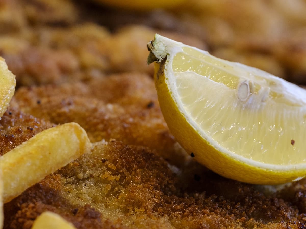Paniertes Schnitzel mit Zitronenscheibe und Pommes frites