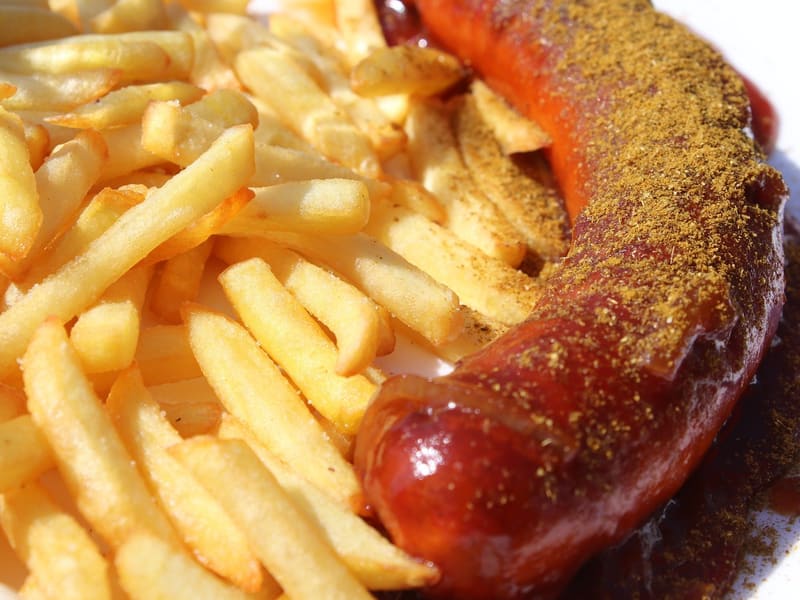 Currywurst mit Currysoße, dazu Pommes frites