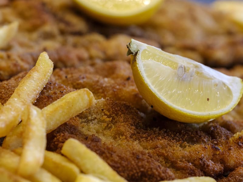Paniertes Schnitzel mit Zitronenscheibe und Pommes frites